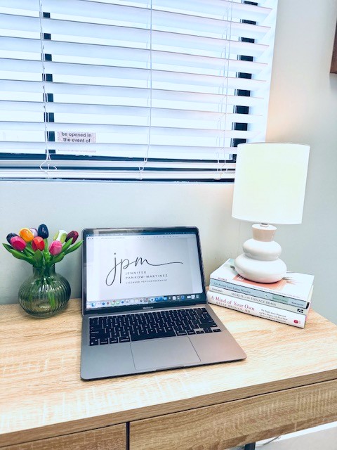 Jennifer's office desk with the JPM logo displayed on a laptop beside colorful tulips and a lamp